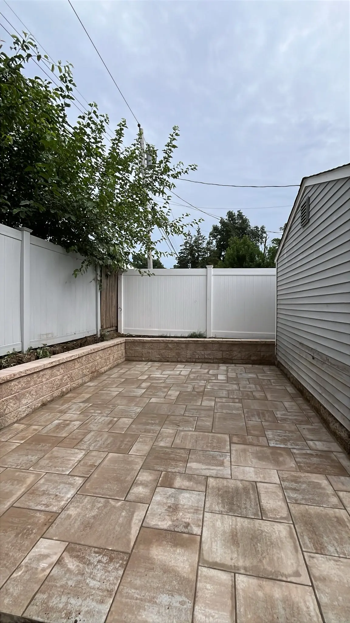 Finished paver patio enclosed by a seating wall and privacy fence
