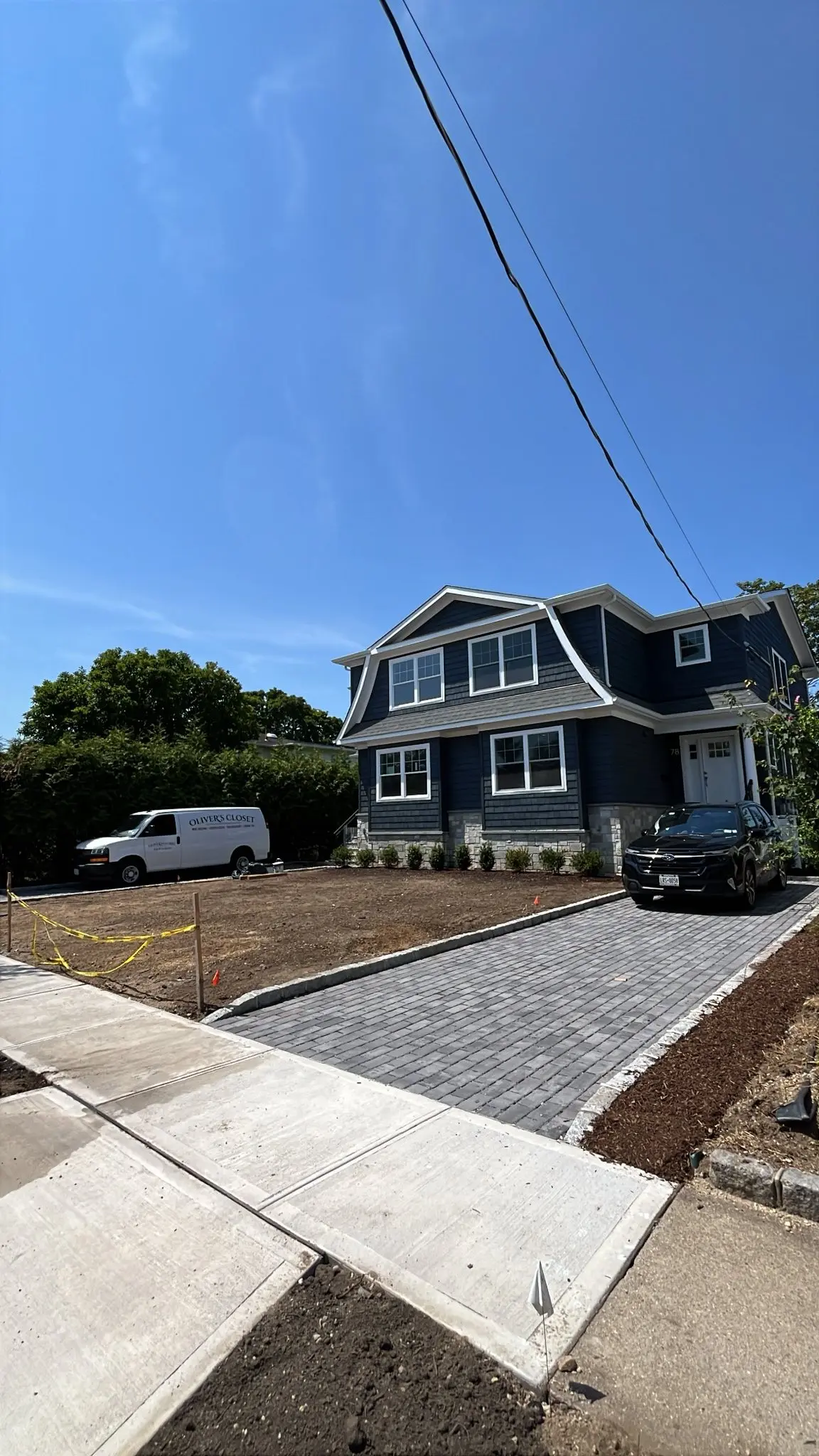 New paver driveway and concrete sidewalk fronting a finished custom home