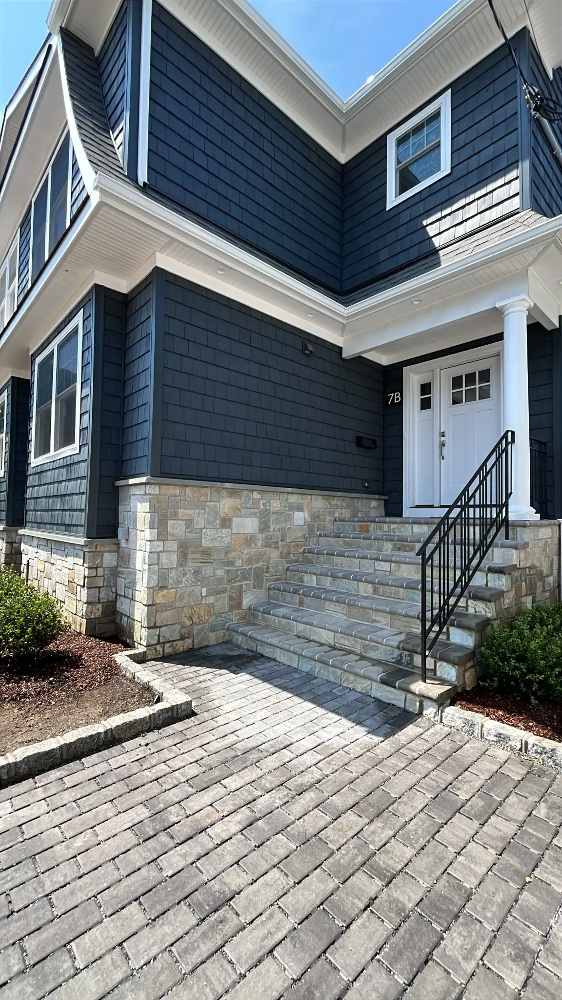 Cobble paver walkway and natural stone entry steps leading to a custom home