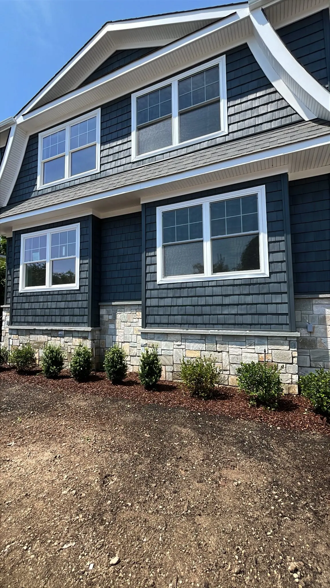 Natural stone veneer foundation on a navy shingle-style custom home